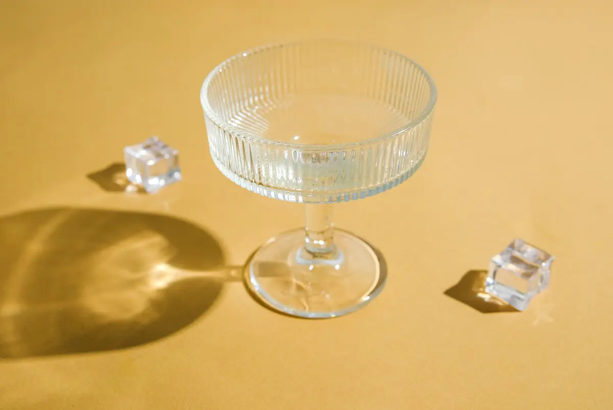 Clear glass and ice cubes on yellow surface
