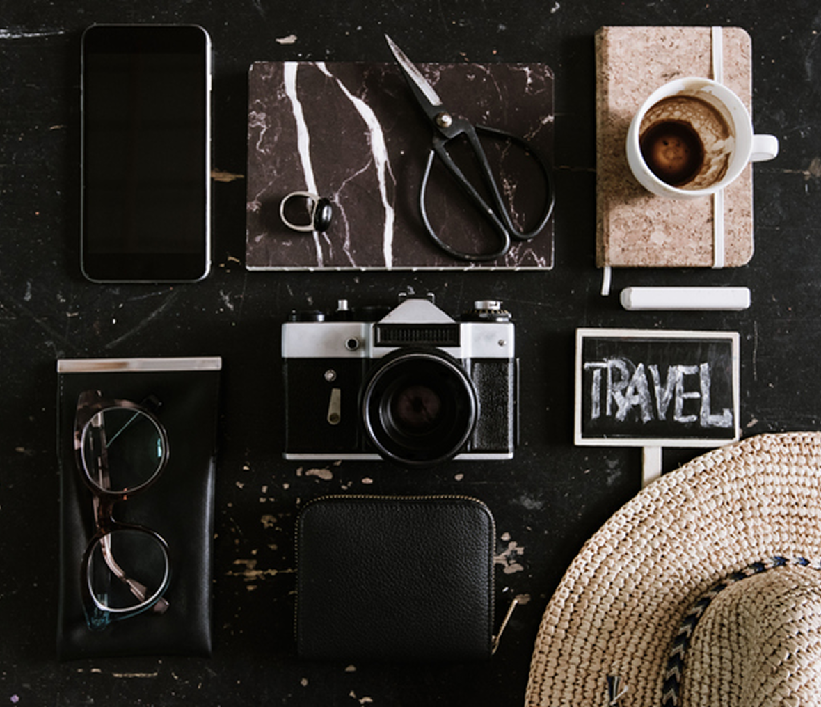 Travel essentials: camera, coffee, phone, straw hat.
