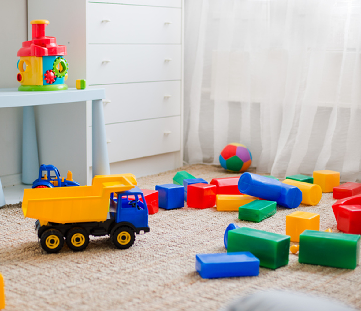 Toy trucks and blocks on carpeted floor.