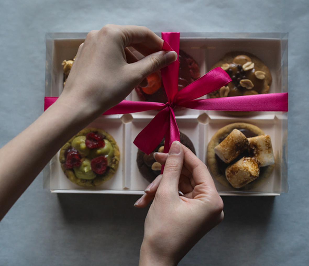 Hands tying ribbon on dessert box.